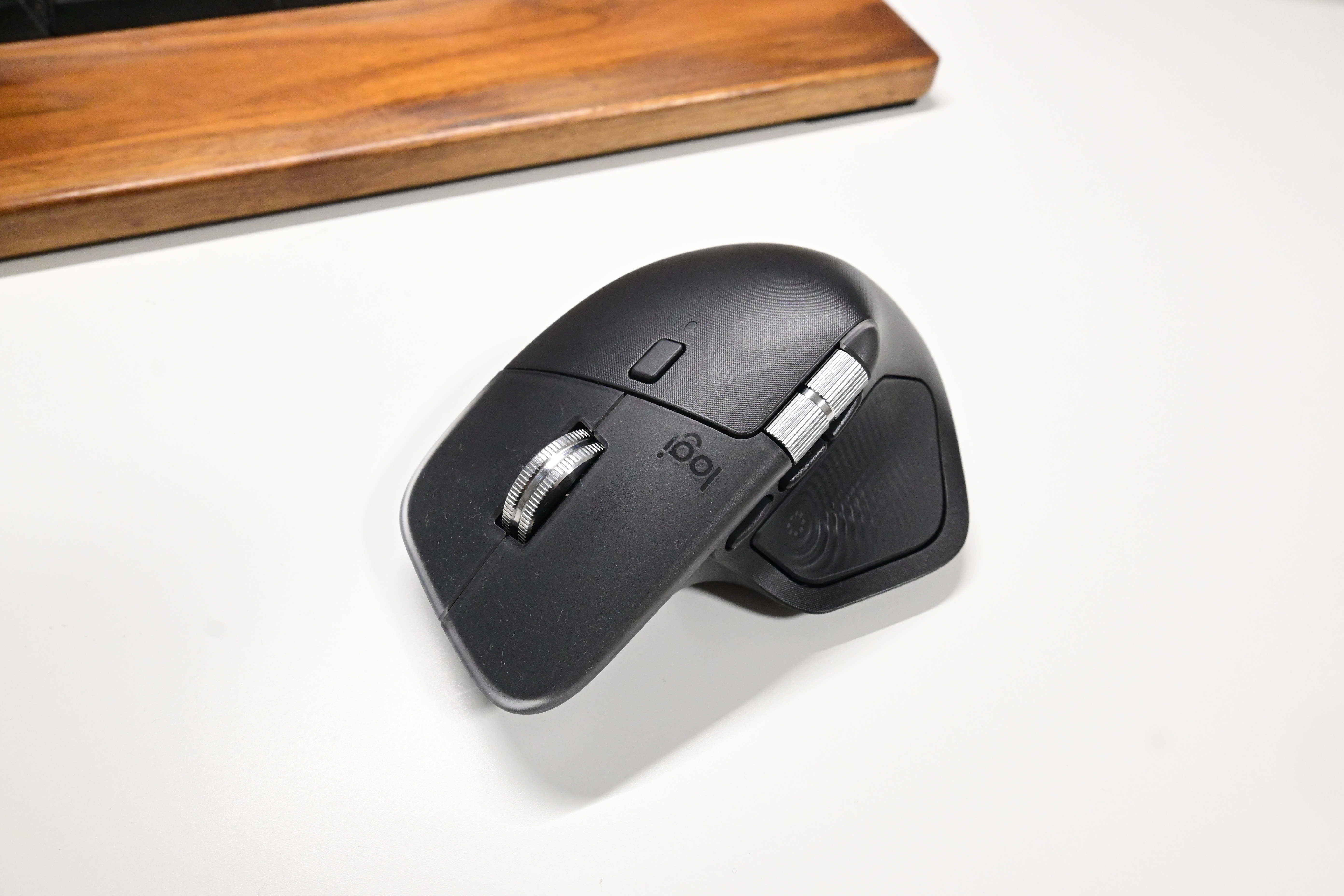 Logicool MX MASTER 4 をデスクの上に置き、奥のウォルナット製パームレストとともに俯瞰で撮影した写真