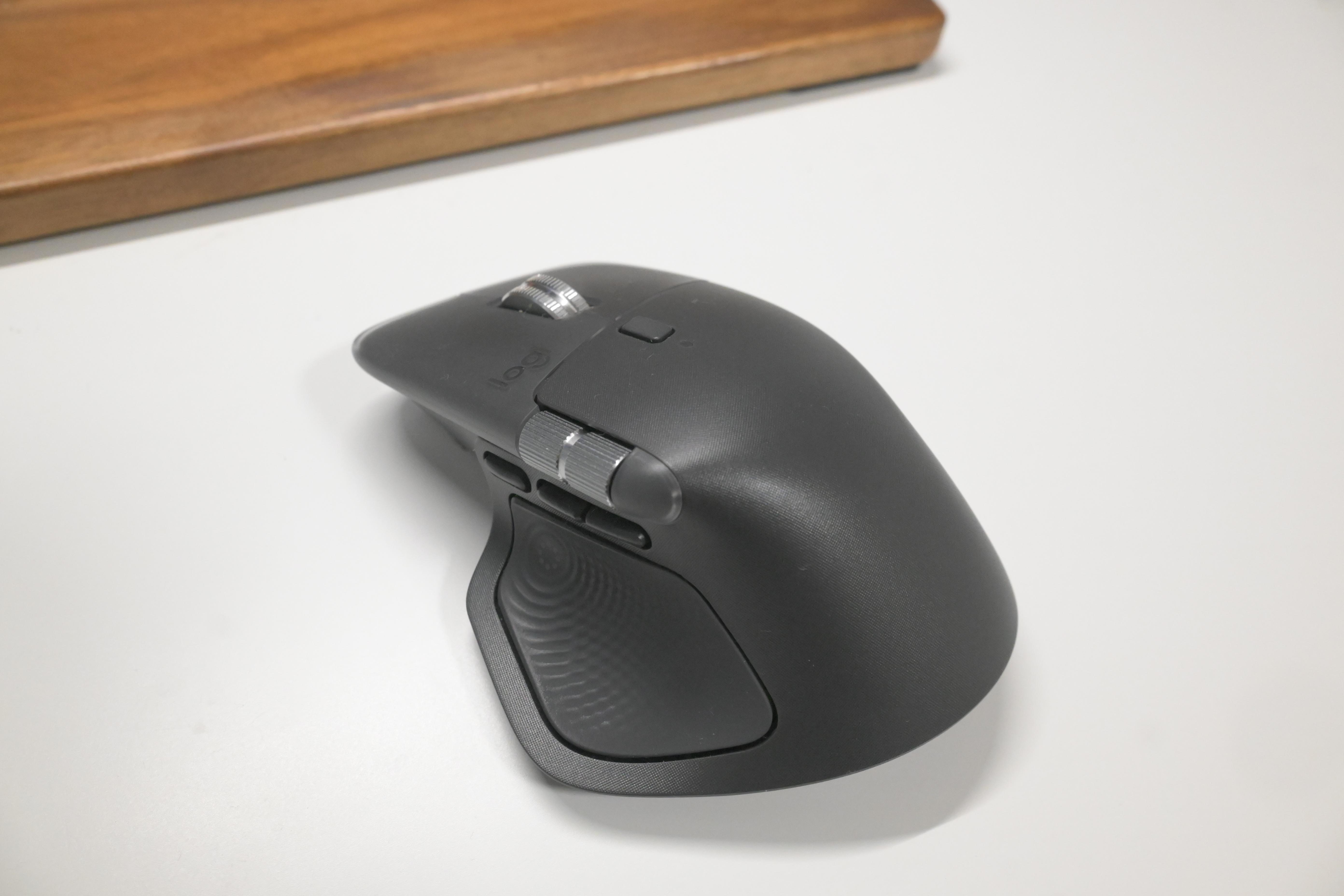 MX MASTER 4 を斜め前方から撮影し、サムホイールとサイドボタン、アクションリングのハプティック面が確認できる写真